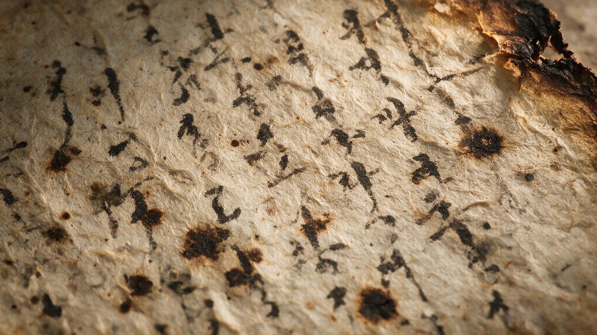 Extreme macro of aged mulberry paper, fibrous texture, blurred black brushstrokes and stains, one corner torn — illegible (AI-generated image)
