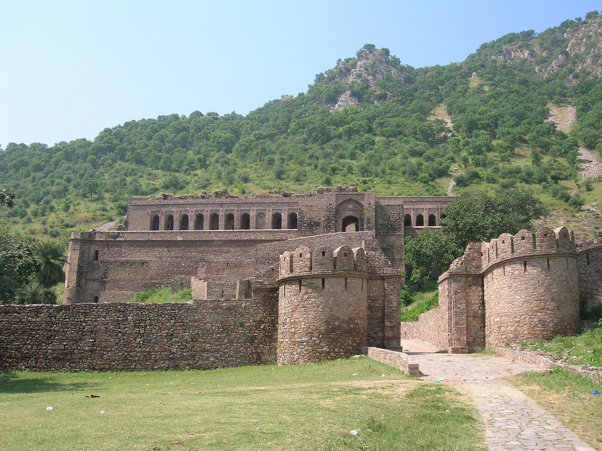 The main gate and round bastion of Bhangarh Fort, with the palace ruins rising behind it