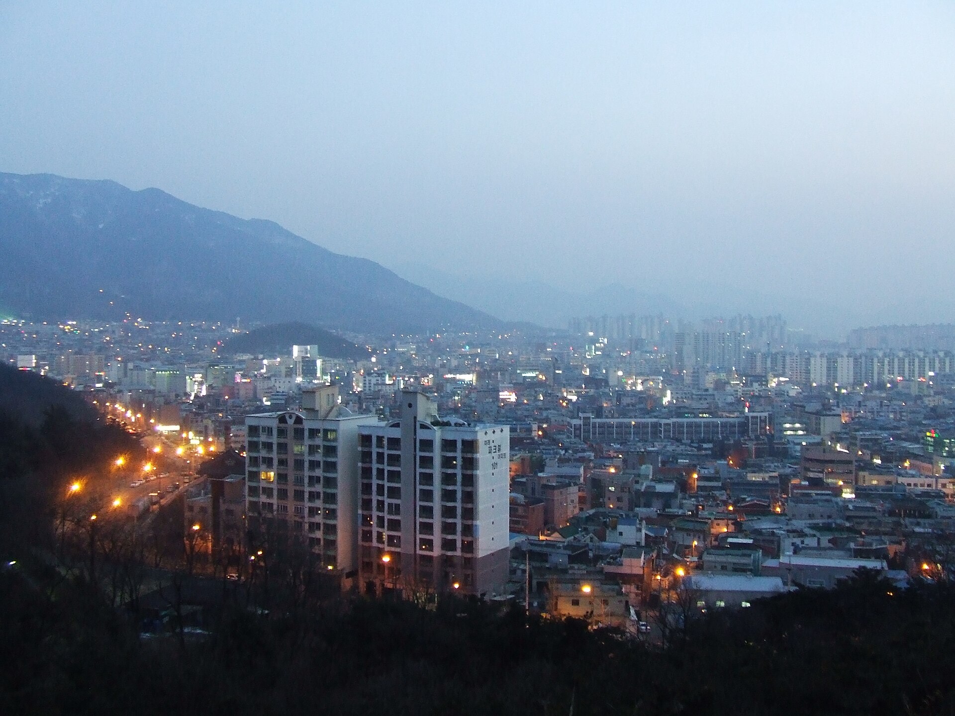 해질녘의 대구 달서구 시가지와 그 뒤로 이어지는 산 능선 — 다섯 아이가 집을 나서 향한 동네 일대의 현재 실경