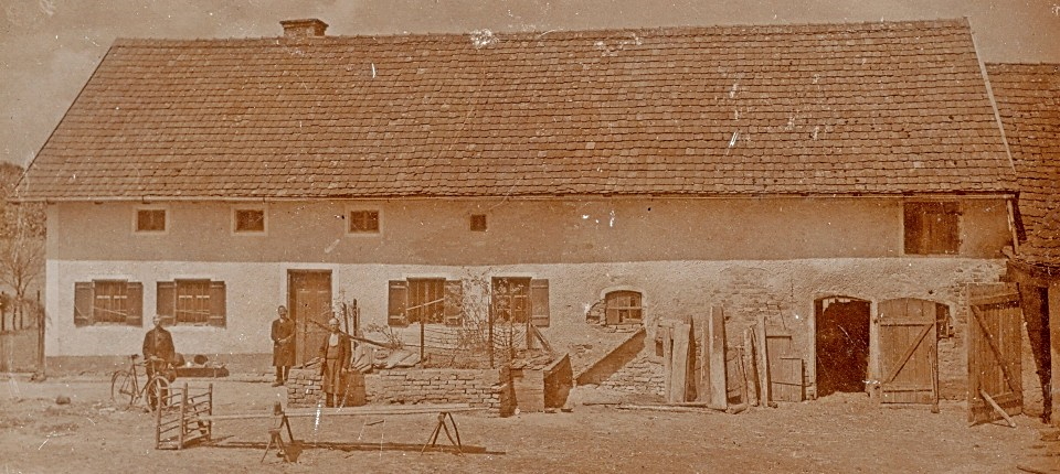 An original sepia photograph of the Hinterkaifeck farmstead before the murders, with people standing in the yard. (Public domain)