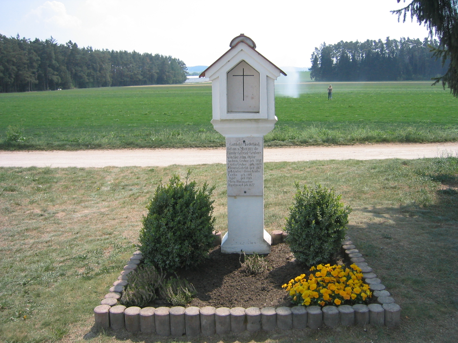 The memorial shrine (Marterl) standing today in the middle of the field where the farmstead once stood, inscribed with the names of the six victims.