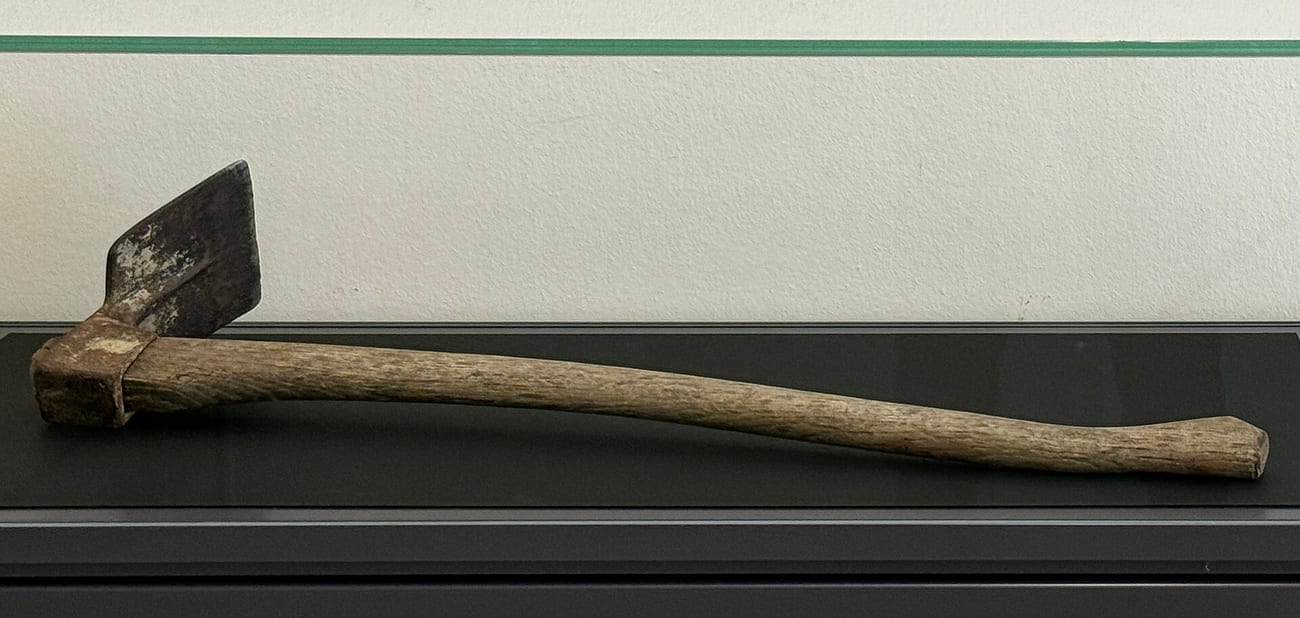 A mattock — the heavy farm tool of the type used as the murder weapon — in a museum case. (Burkhard Mücke / CC BY-SA 4.0)
