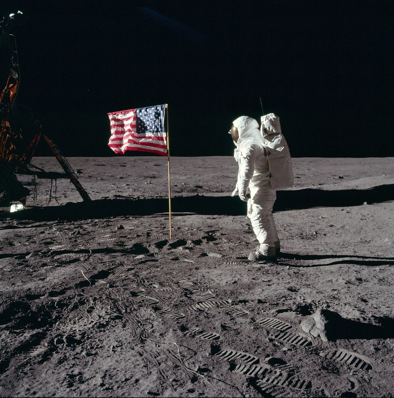 Aldrin salutes the flag. The sky behind is pure black — the second "clue" skeptics point to. (NASA / Neil A. Armstrong / Public domain)