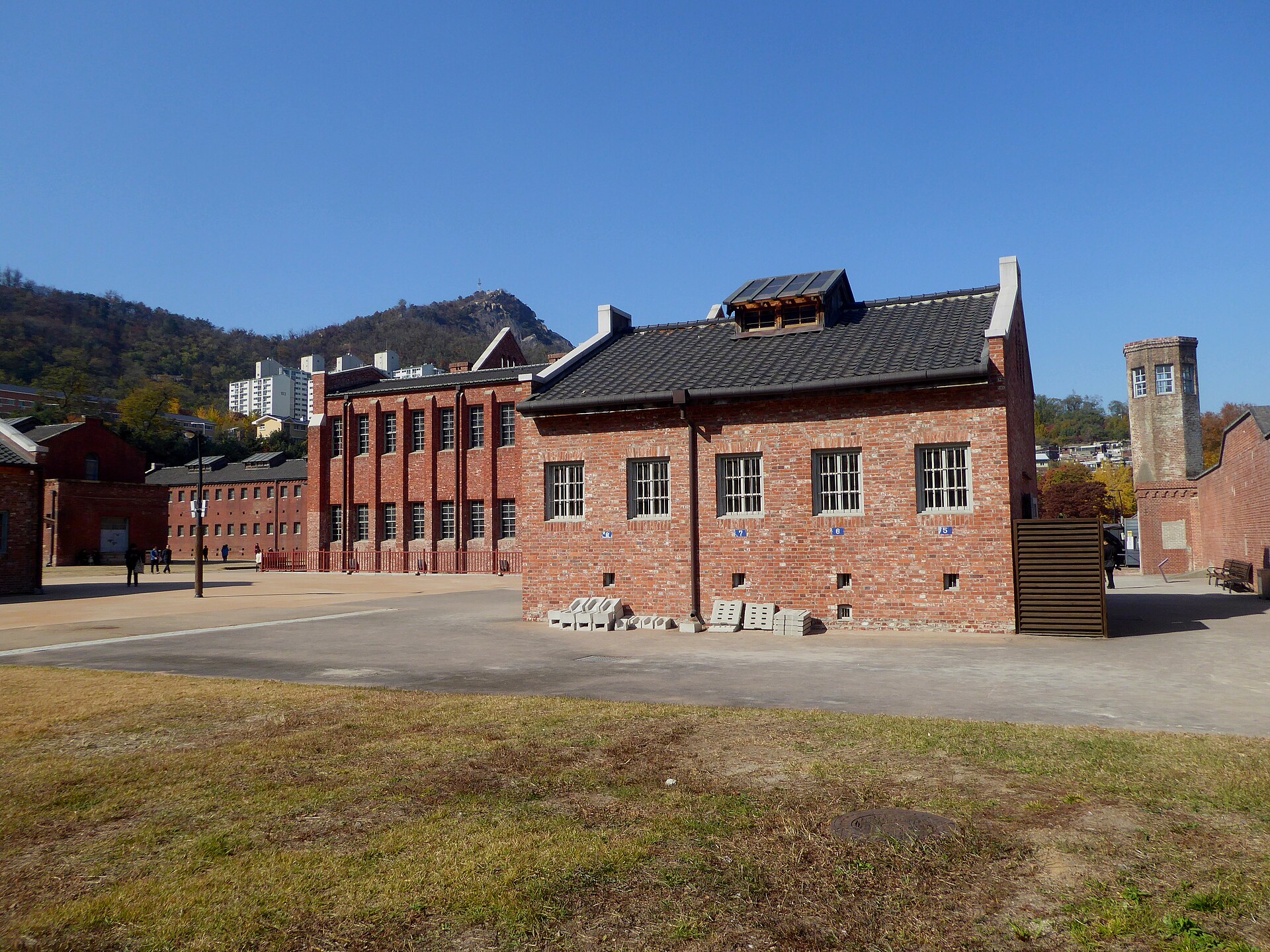 The red-brick cell blocks and watchtower of the former Seodaemun Prison, seen from outside — a stand-in location, not Busan Prison